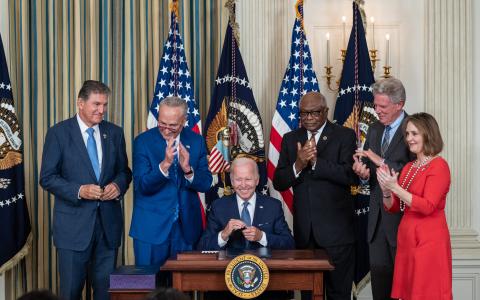 Congressional Democrats with President Biden signing the Inflation Reduction Act
